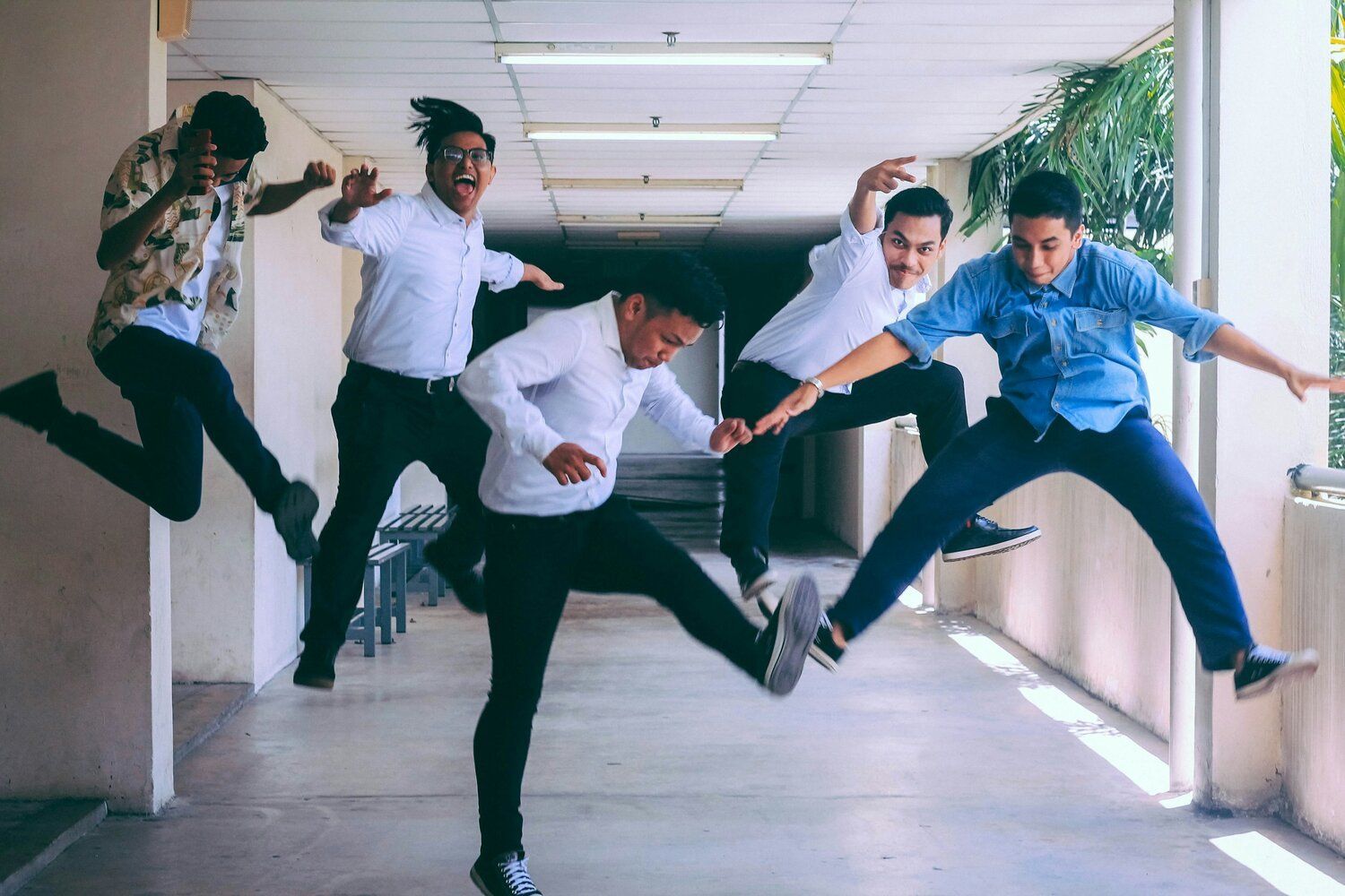 A group of young men are jumping in the air in a hallway.