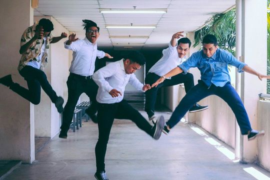 A group of young men are jumping in the air in a hallway.
