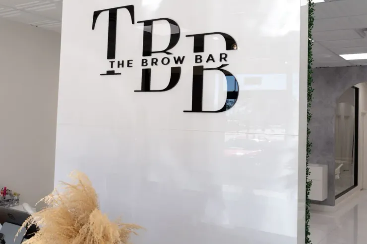 The Brown Bar logo on a white glass wall at a salon entrance