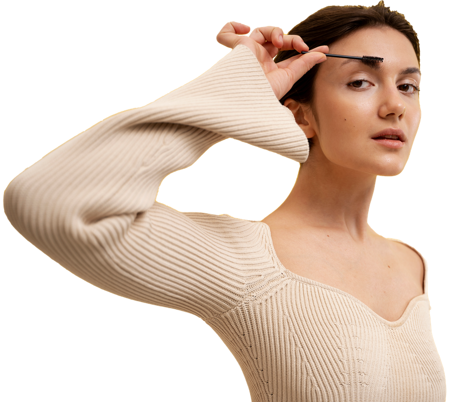 Woman in a cream knit sweater posing against a white background, hand near her eyebrow.