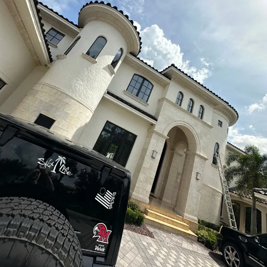 Black Jeep in front of a large, light-colored house with an arched entrance and a tower.