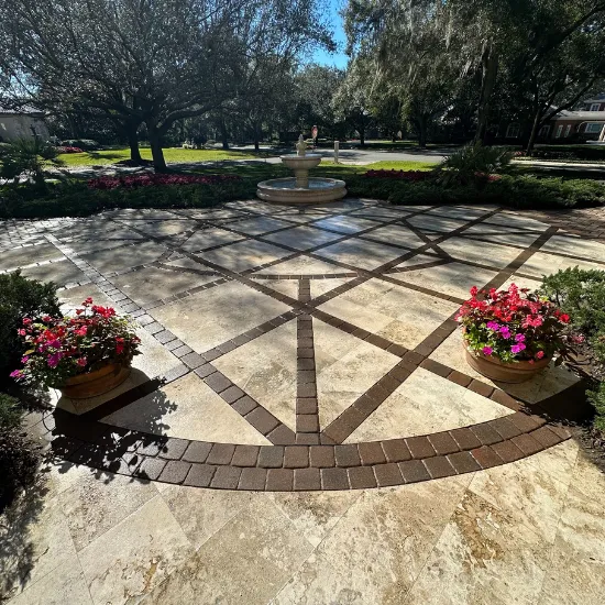 Patio with patterned tile, flower pots, and a fountain in a garden setting.