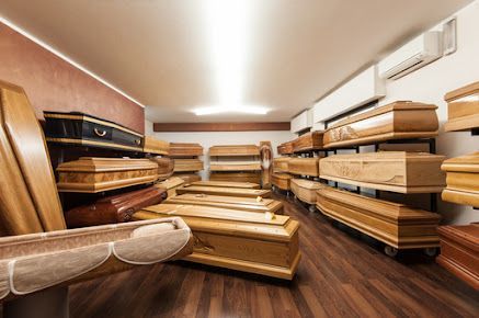 Bare di legno esposte nello showroom di un'agenzia di pompe funebri con pavimenti e scaffali in legno.