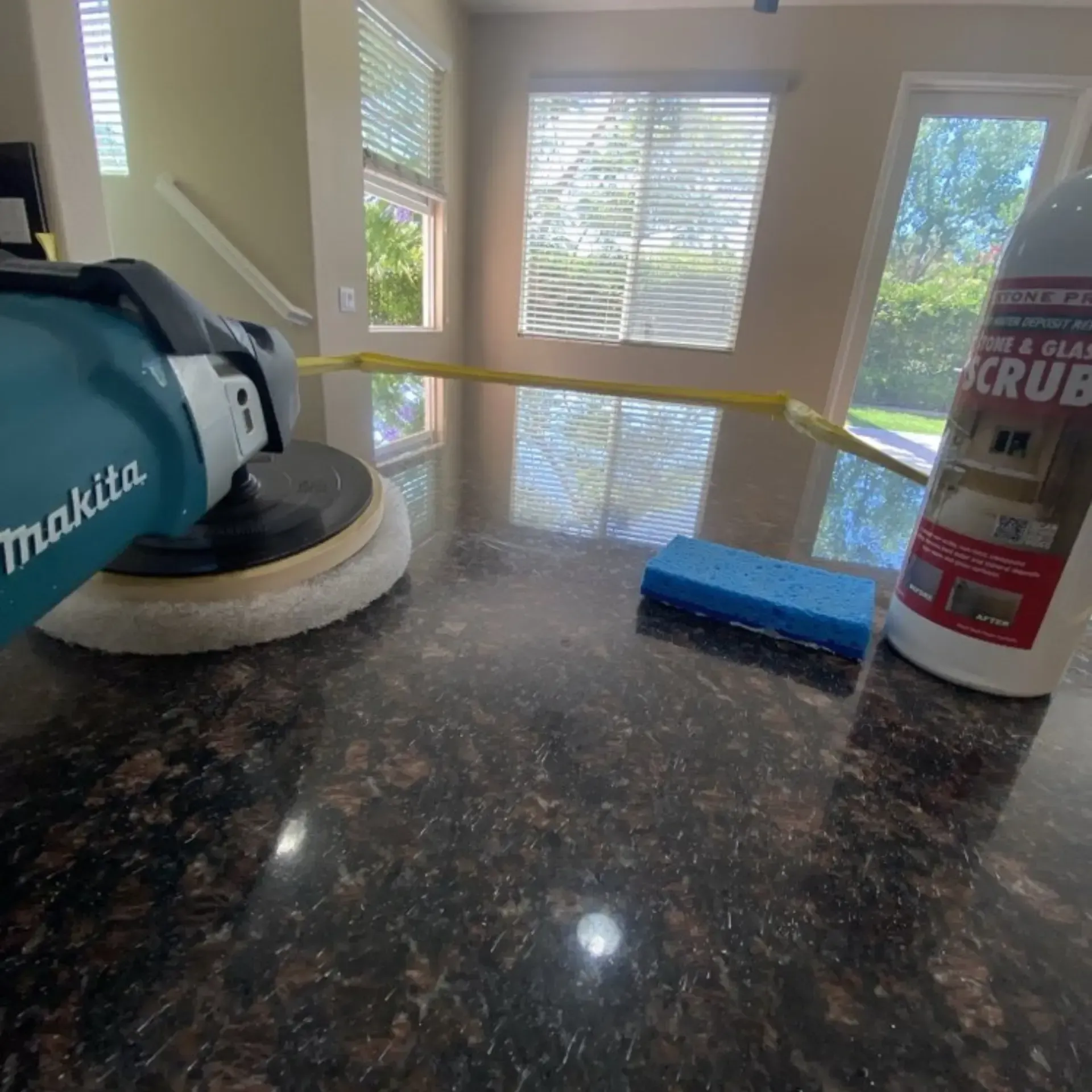 A makita polisher is sitting on a counter next to a bottle of scrub.