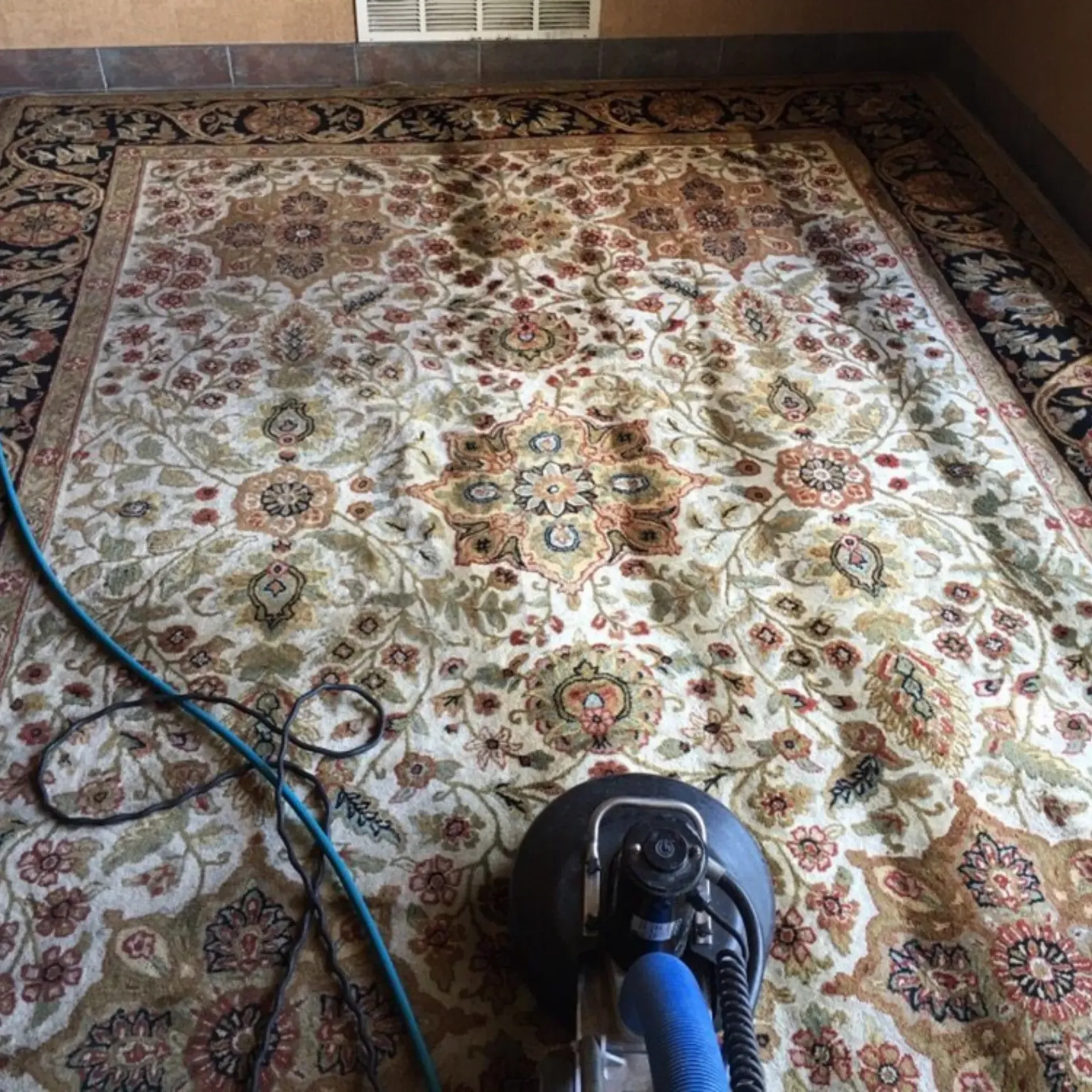 Powerhouse Carpetcleaning - A rug is being cleaned with a machine in a living room.
