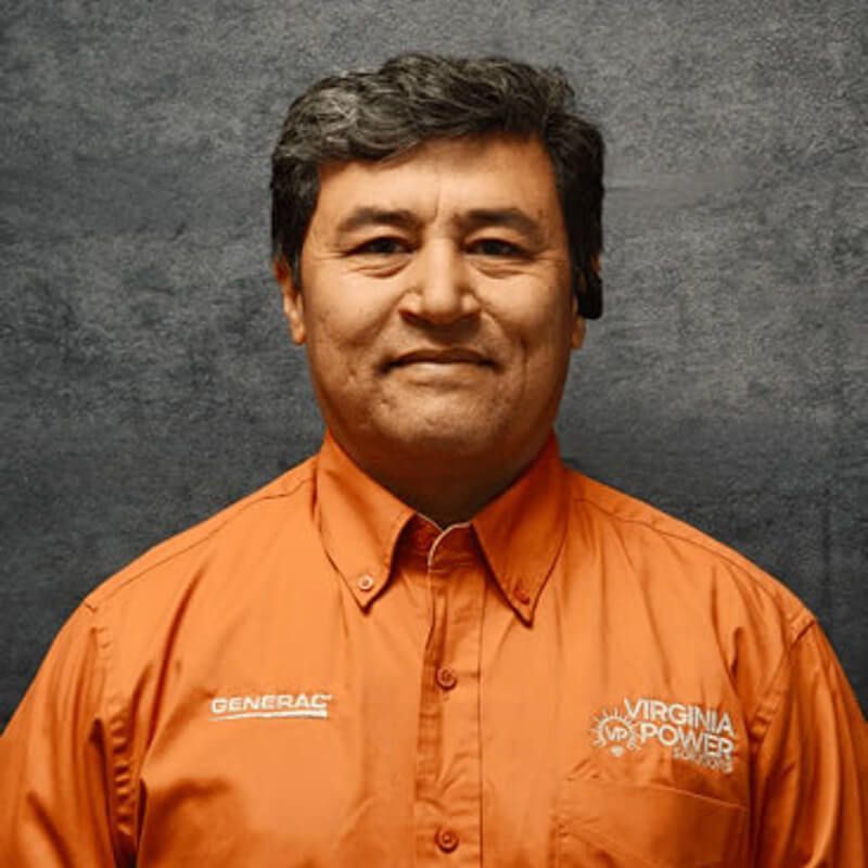 Man in orange Virginia Power shirt, smiles at the camera, against a textured gray background.