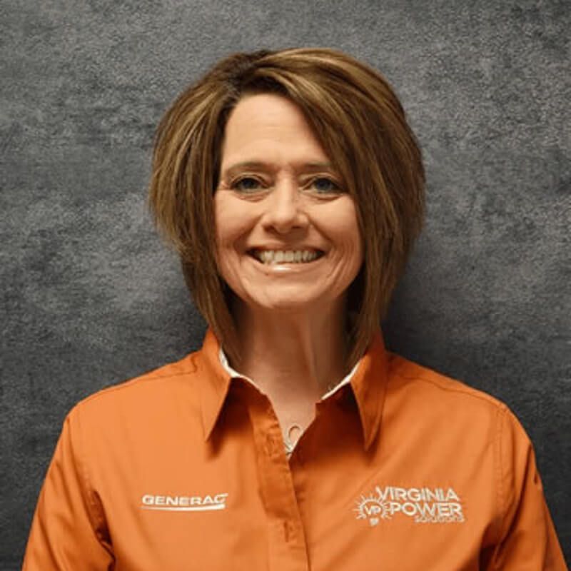 Woman in an orange Virginia Power shirt smiles, standing in front of a gray backdrop.