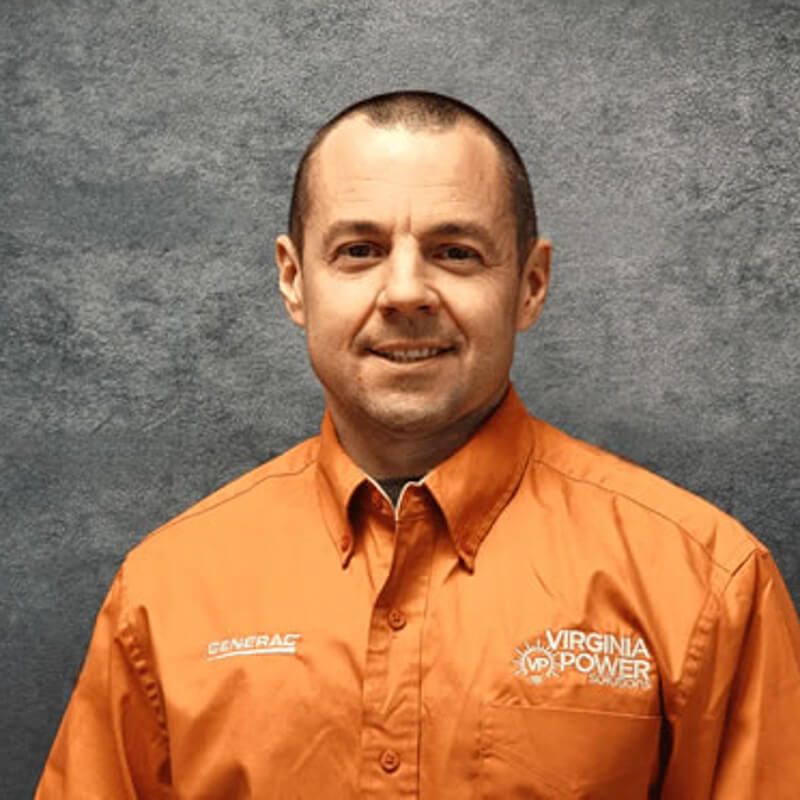 Man in orange Virginia Power shirt smiles in front of a gray backdrop.