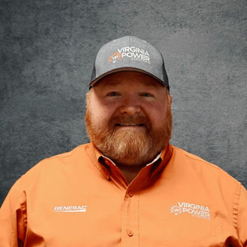 Man wearing a Virginia Power hat and shirt smiles at the camera against a grey background.