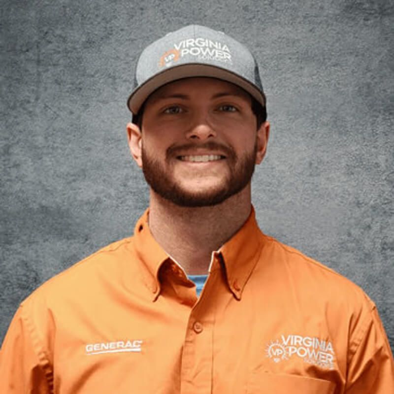 Man wearing a Virginia Power hat and orange work shirt smiling in front of a gray background.