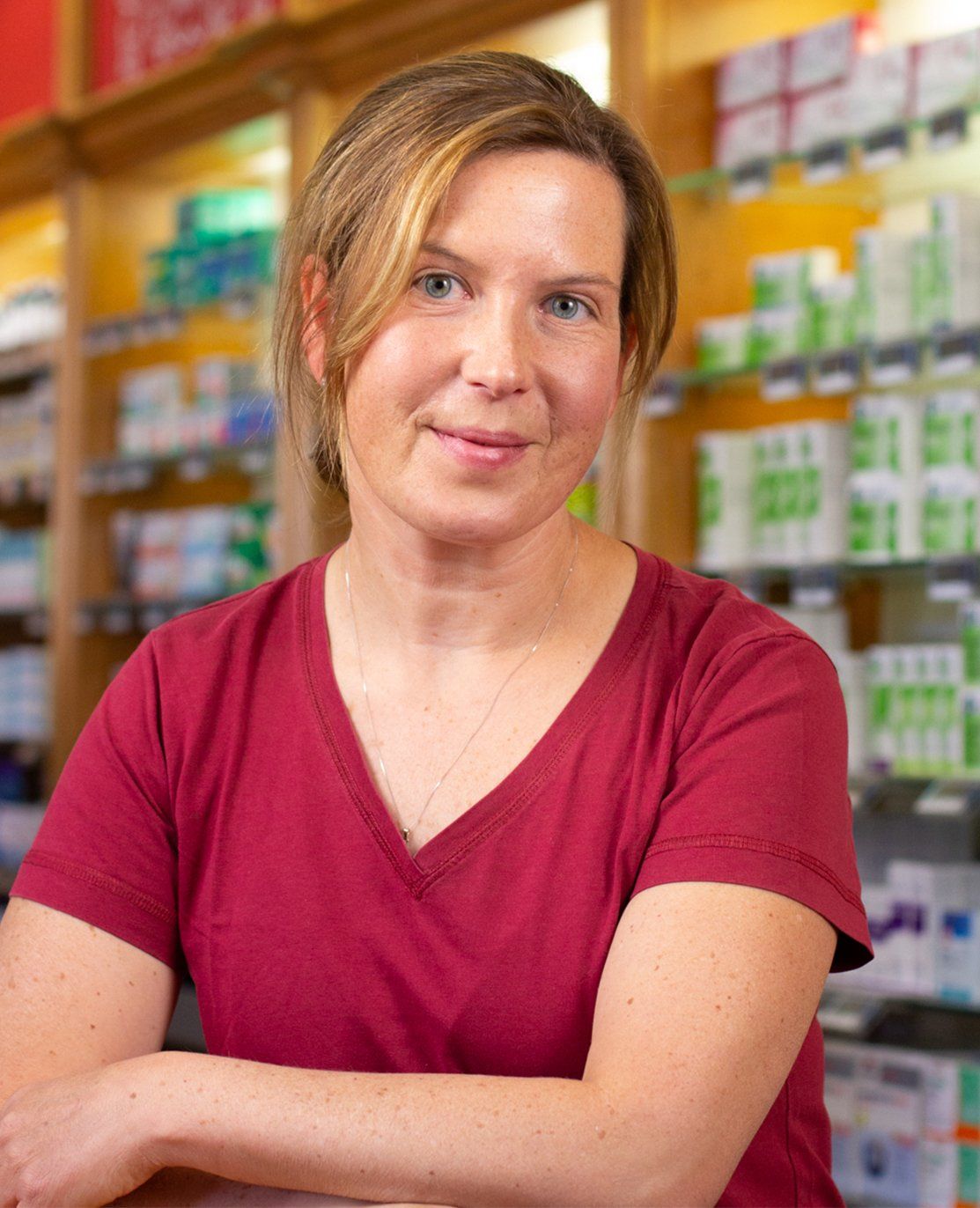 Eine Frau in einem roten Hemd posiert für ein Foto in einer Apotheke