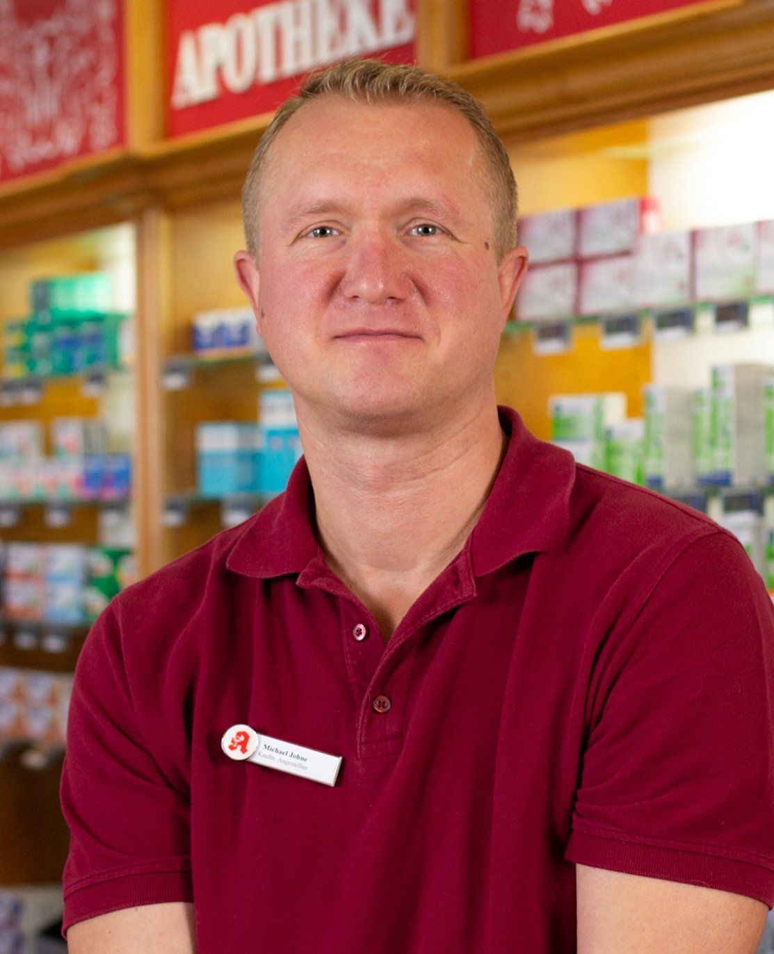 Ein Mann im roten Hemd steht vor einer Apotheke