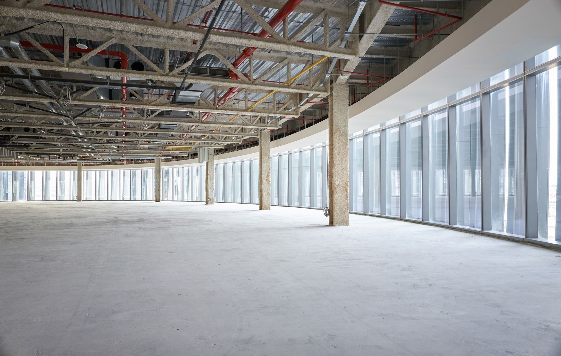 Construction workers on a concrete rooftop at sunset, with cranes, buildings, and a cloudy sky in the background.