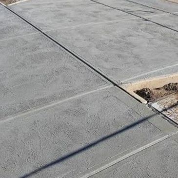 Newly poured gray concrete sidewalk sections, some with seams.