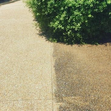 A concrete sidewalk with a distinct color difference. One side is clean and light, the other is dirty and dark, likely due to power washing.