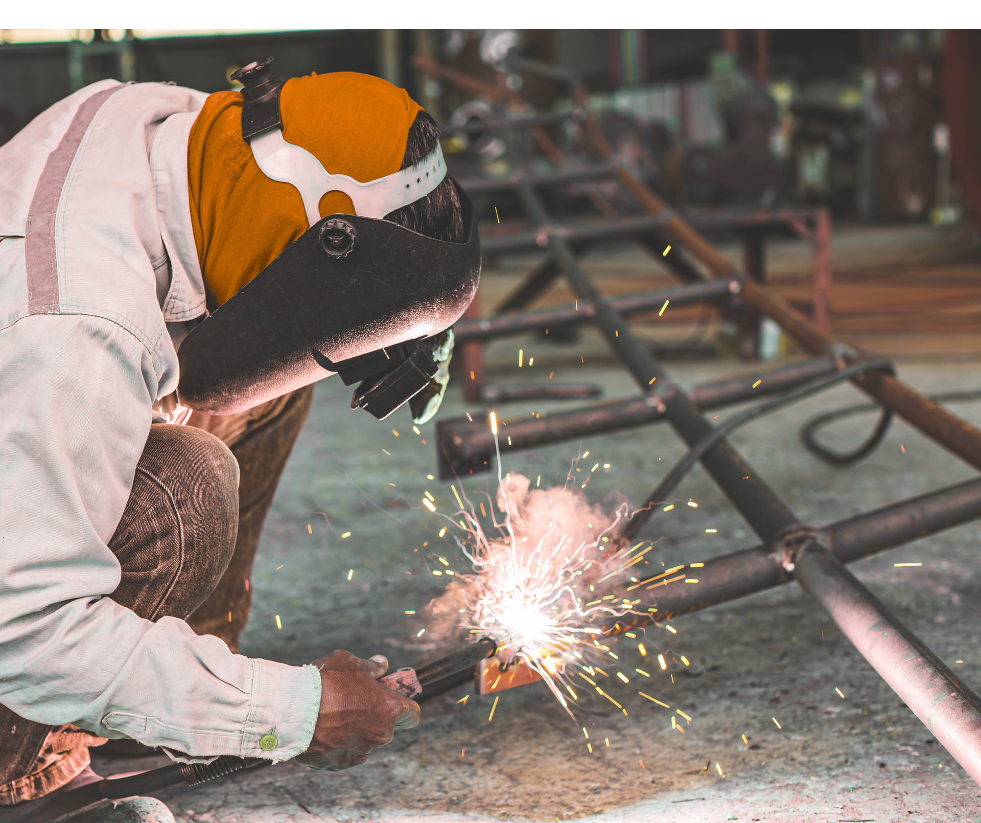 A man is welding a piece of metal in a factory.