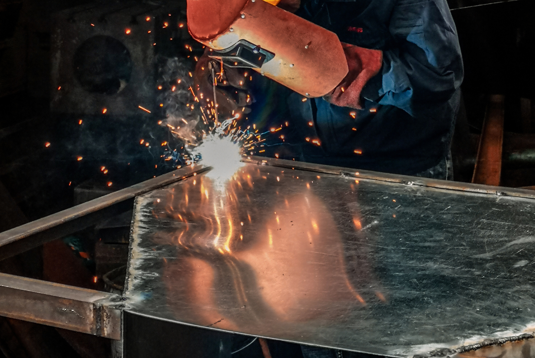 A man is welding a piece of metal in a factory.