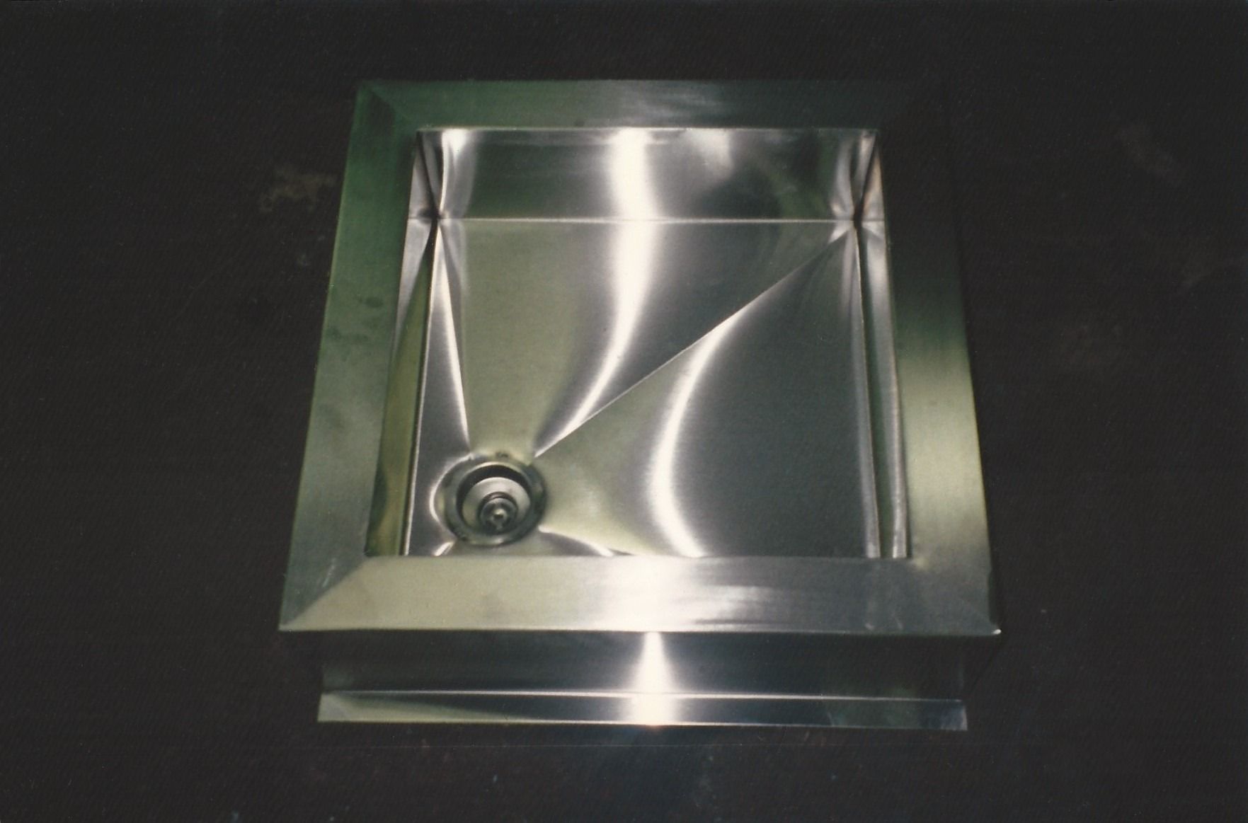 Two men are welding a piece of metal in a factory.