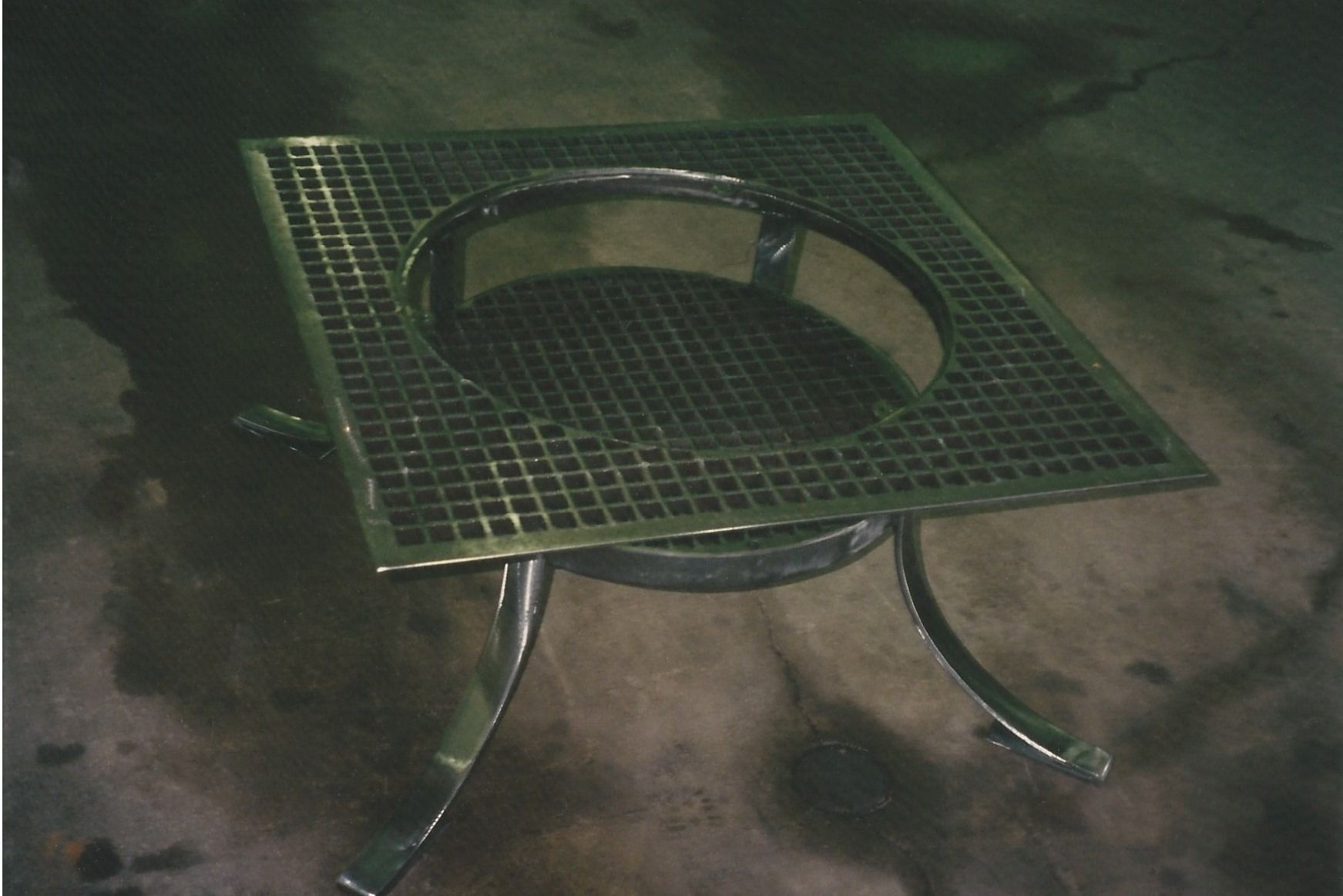 A man wearing a welding mask is grinding a piece of metal in a factory.