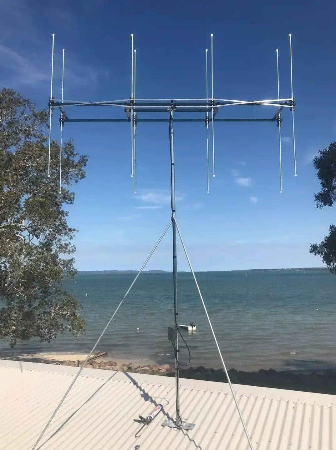 A Large Antenna Is Sitting On A Roof Near The Ocean — Bradshaws Radio & TV Service In Maryborough, QLD
