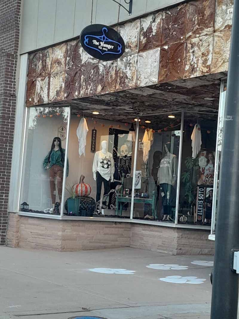 A storefront with mannequins displaying clothing; rusty-looking ceiling.