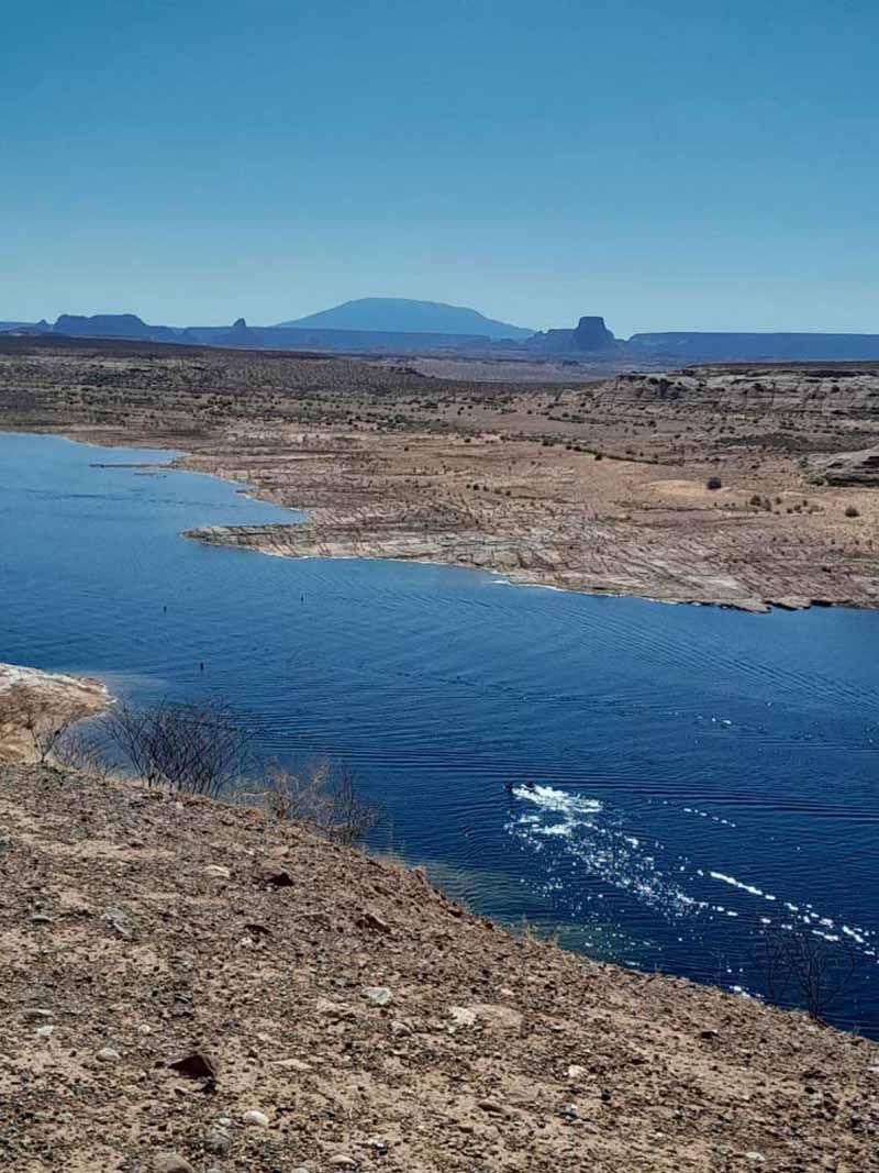 Blue river flows through a desert landscape under a clear sky.