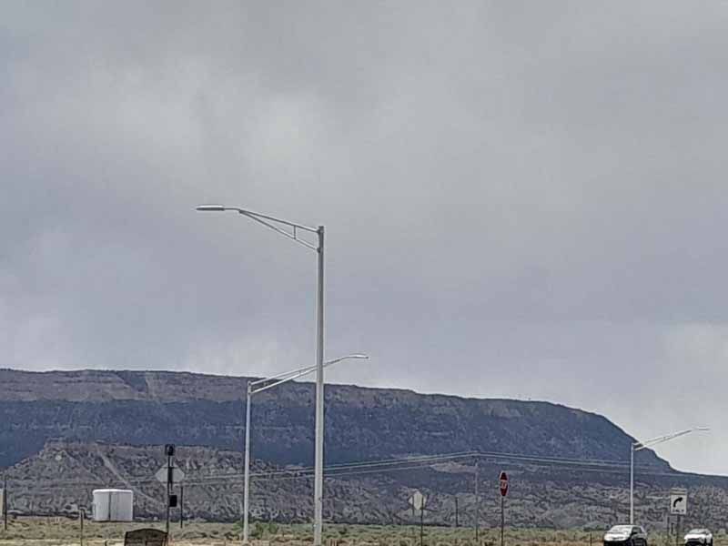 Gray sky over a distant mountain. Street lights and a road in the foreground.