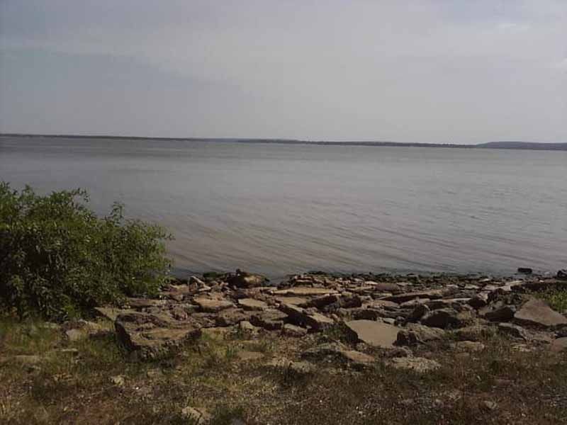 Calm water with rocky shoreline under a cloudy sky.