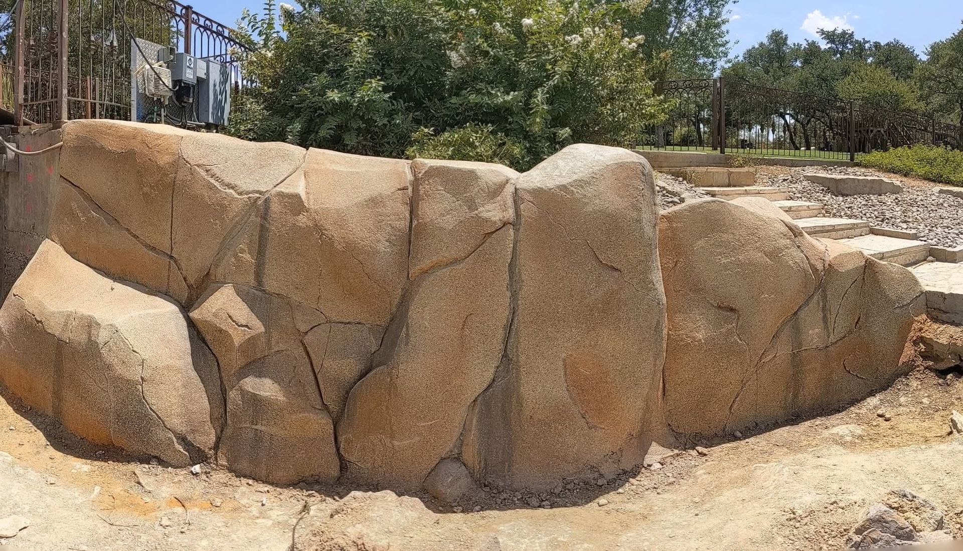 Swimming pool with waterfall, rock formation, and water slide on a sunny day.