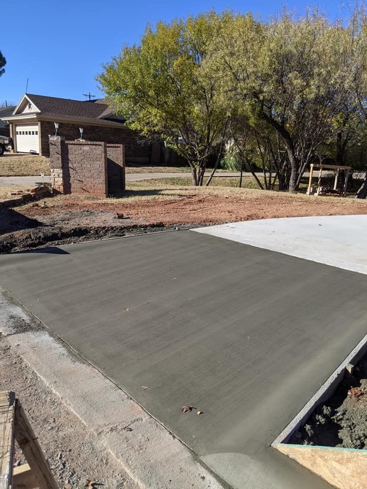 Freshly poured concrete driveway, gray in color, in front of a house on a sunny day.