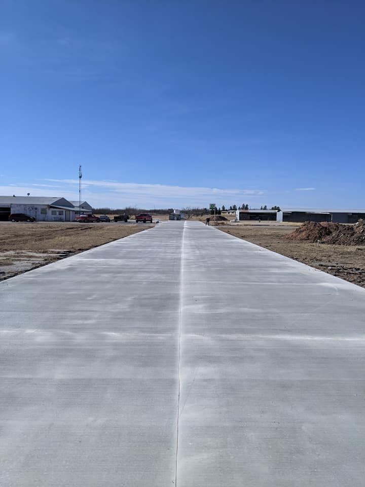 Concrete road leading towards buildings under a clear, blue sky.