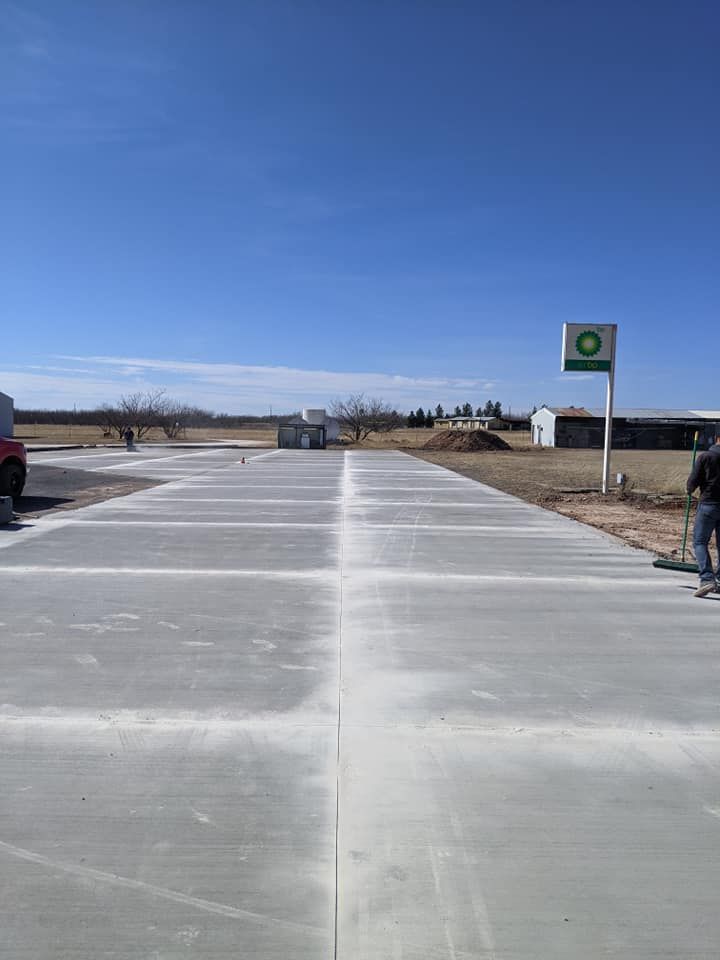 New concrete driveway under construction at a BP gas station on a sunny day.