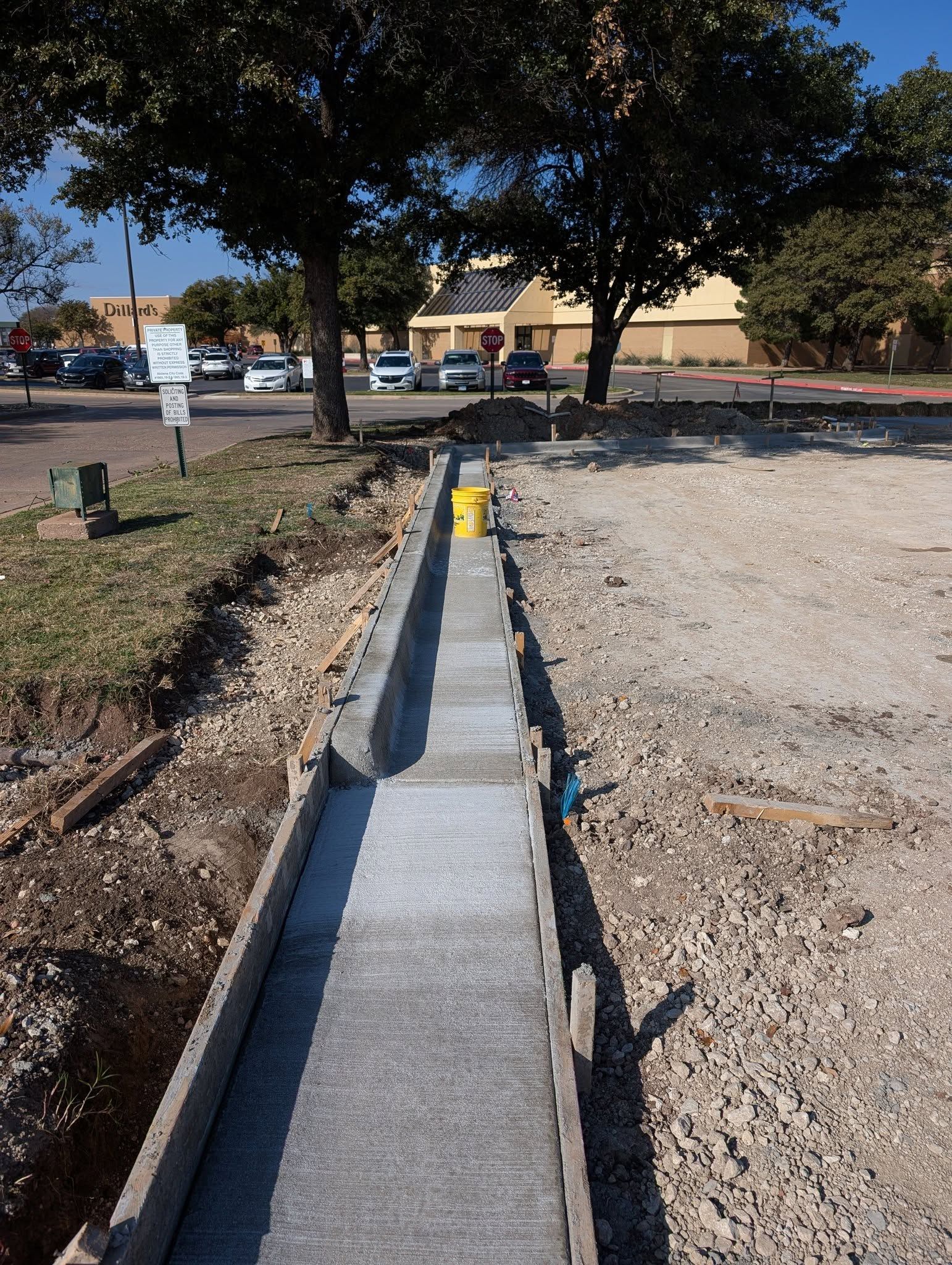 Concrete drainage channel under construction next to a parking lot.