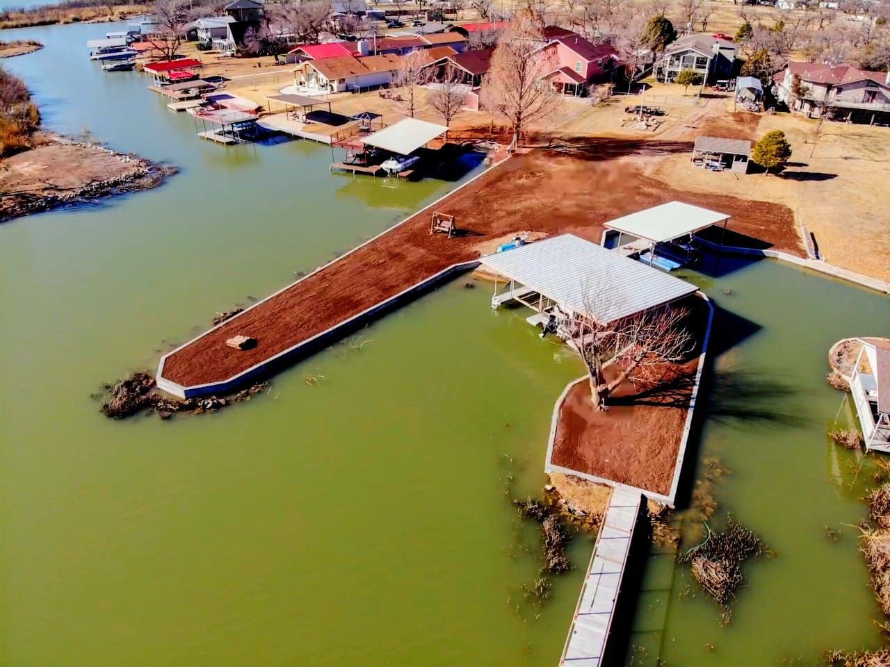 A person spraying a large, gray concrete surface with a building and sky in the background.
