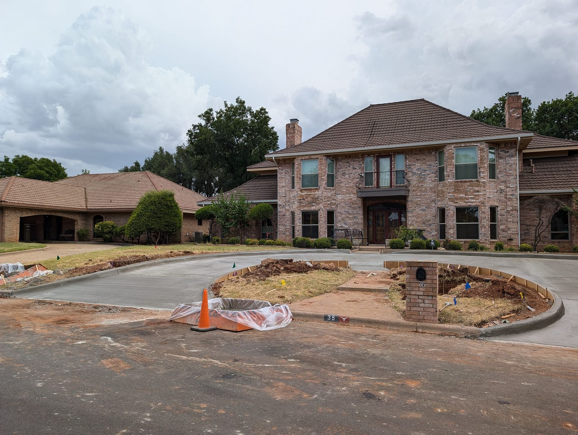 Large brick house with a circular driveway; construction debris visible.