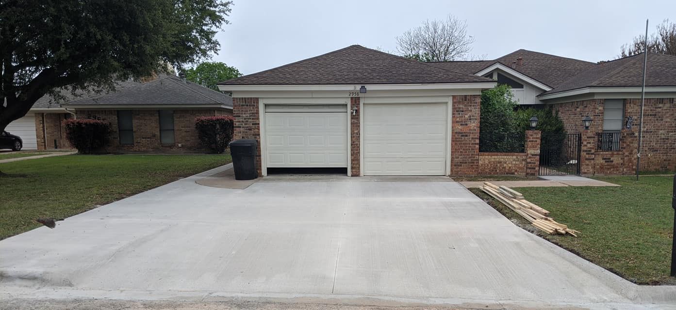 Two-car garage with one door open, in front of a house with a concrete driveway.