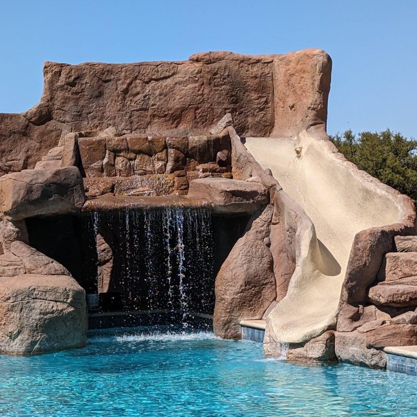 Backyard with pool, hot tub, gray pavers, green turf, and construction equipment.