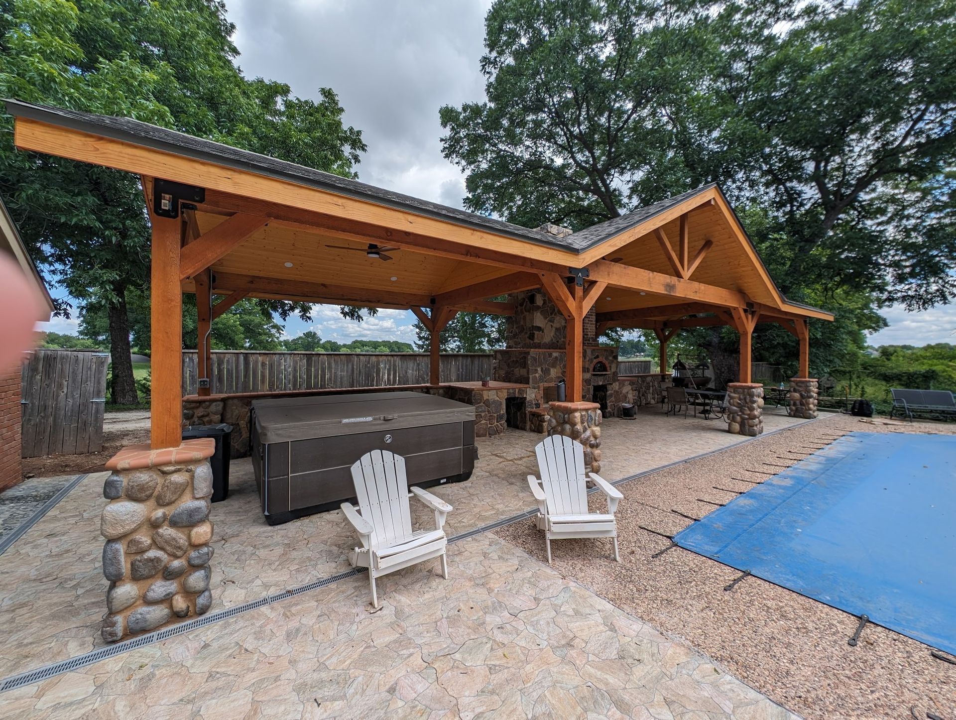 Outdoor covered structure with a hot tub, pool, and seating.