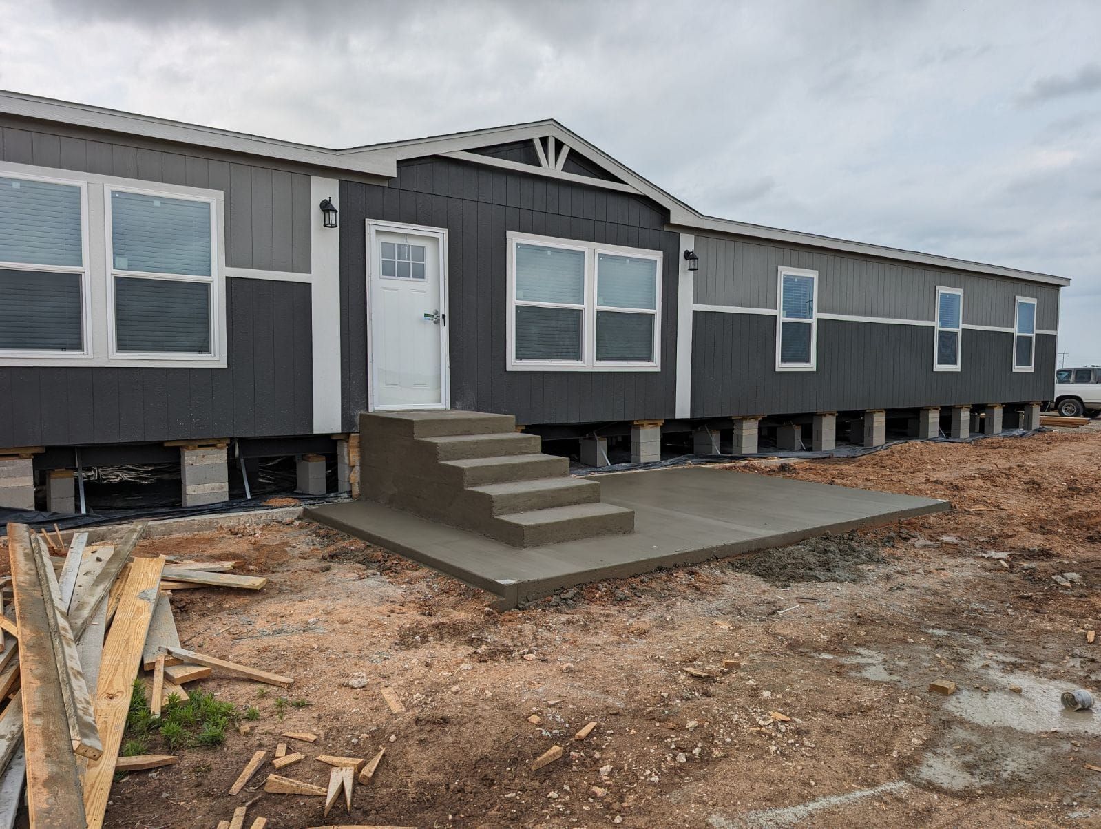 Gray and white house with concrete steps and landing under construction.