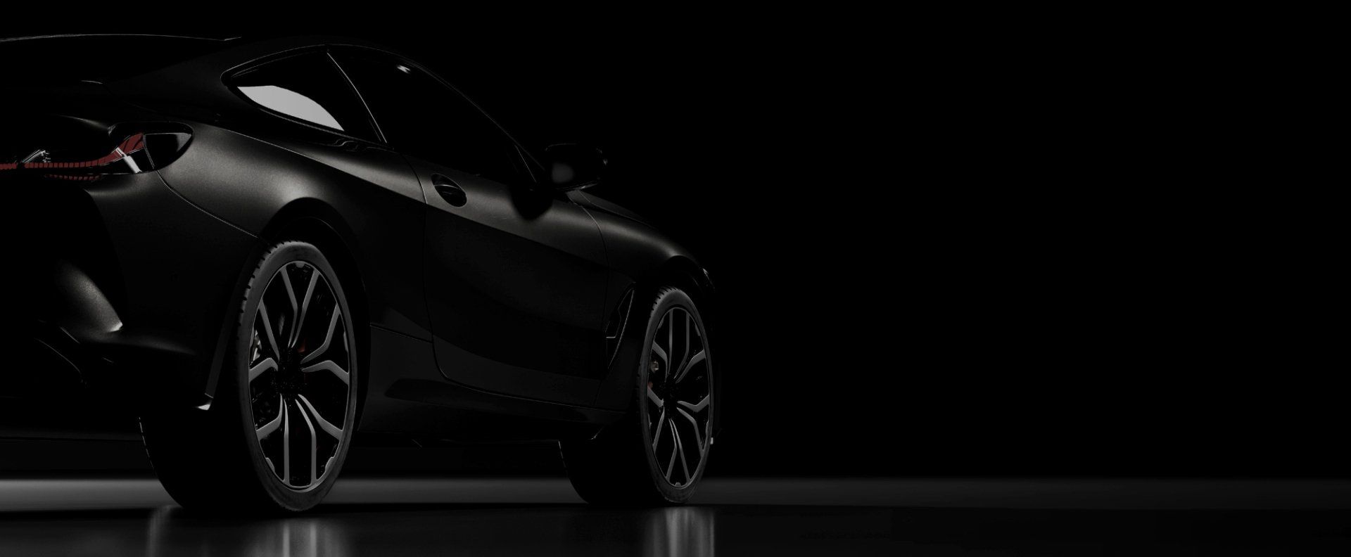 Black sports car with silver rims, angled, on a dark reflective surface | J & J Elite Auto Repair