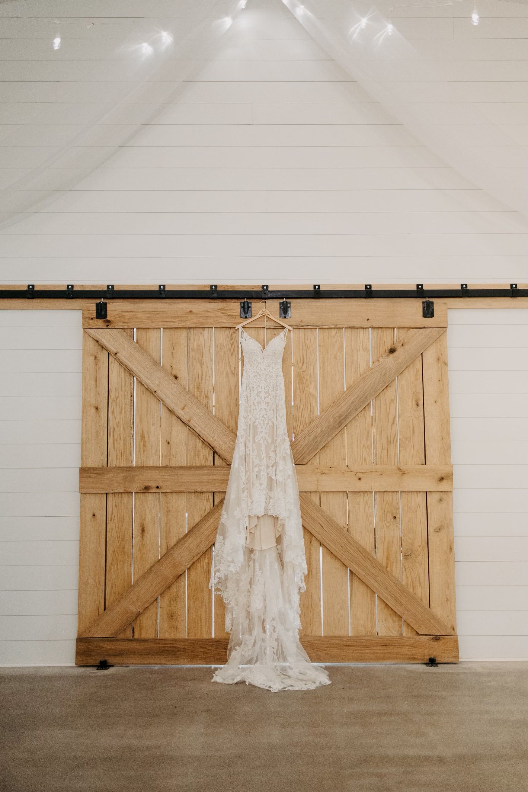 A wedding dress is hanging on a wooden sliding barn door.
