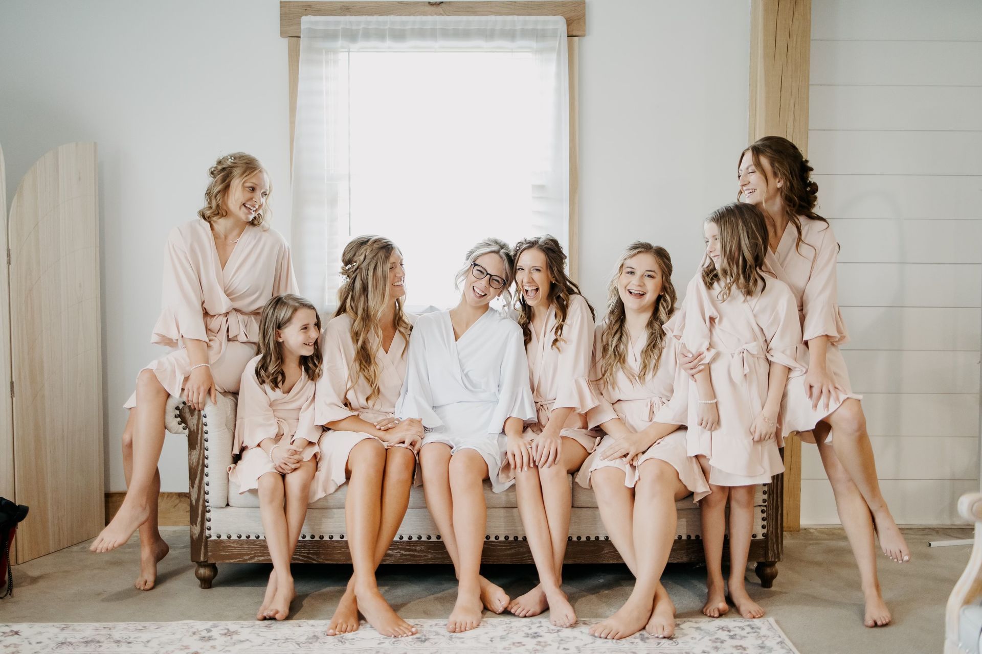 A bride and her bridesmaids are sitting on a couch.