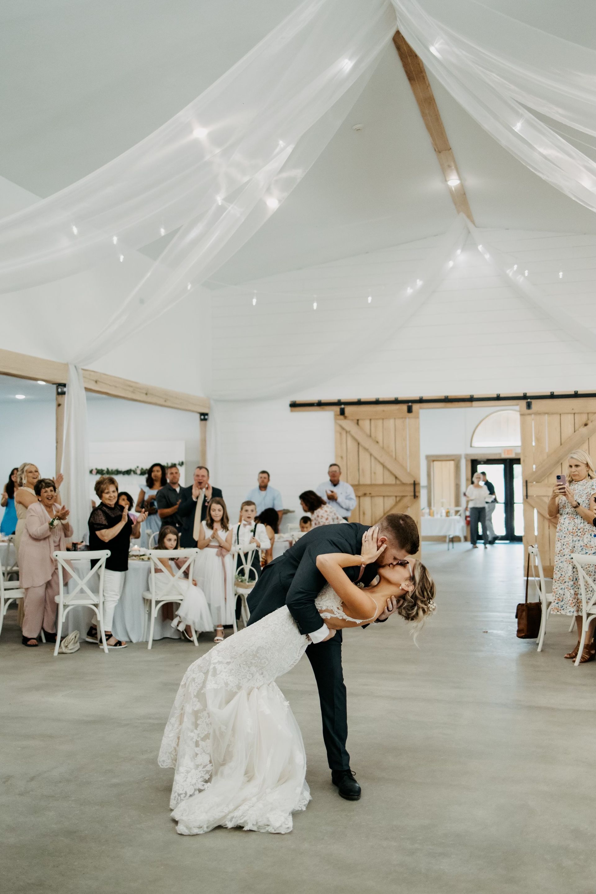 A bride and groom are kissing during their first dance at their wedding reception.