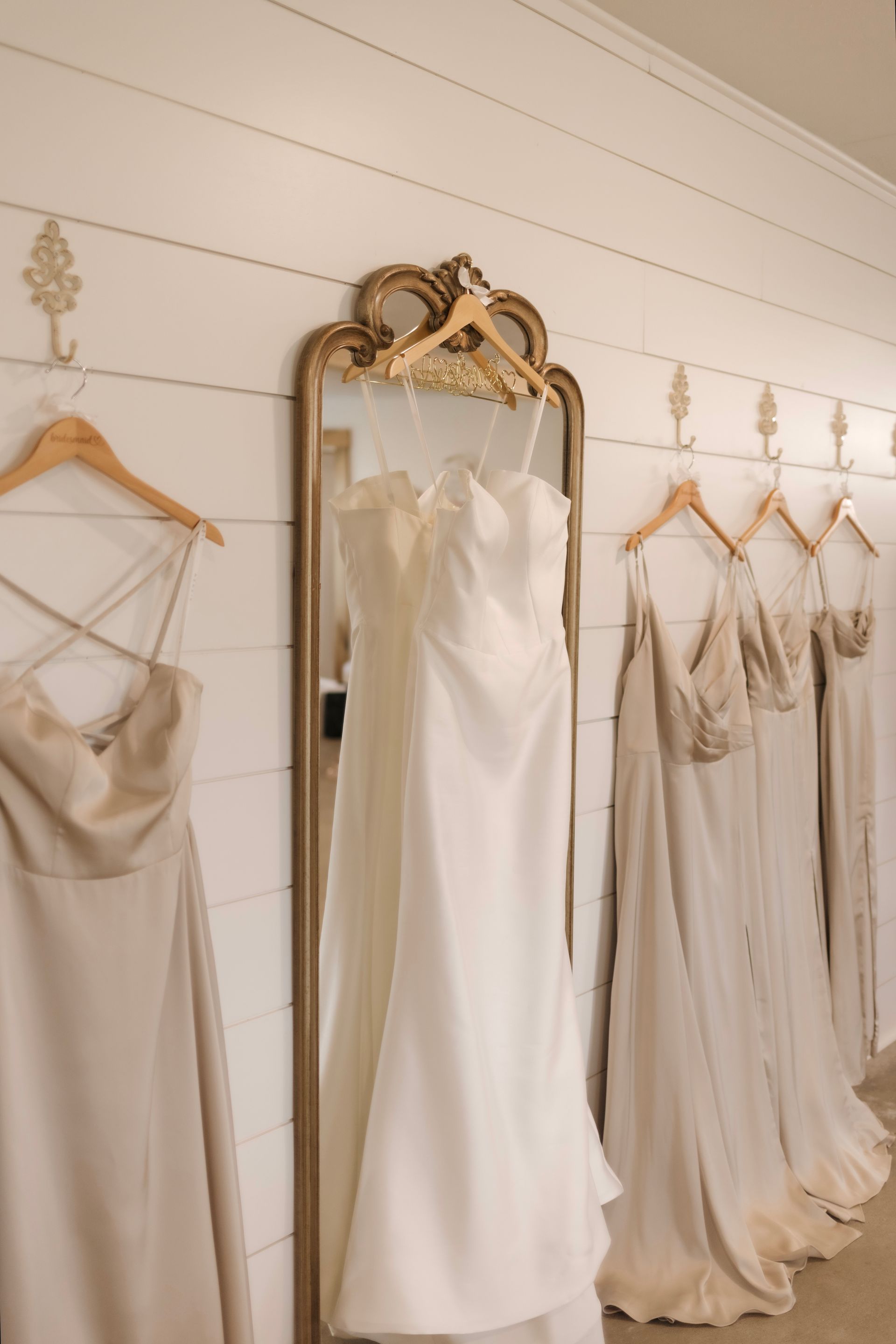 A row of wedding dresses hanging on a wall next to a mirror.