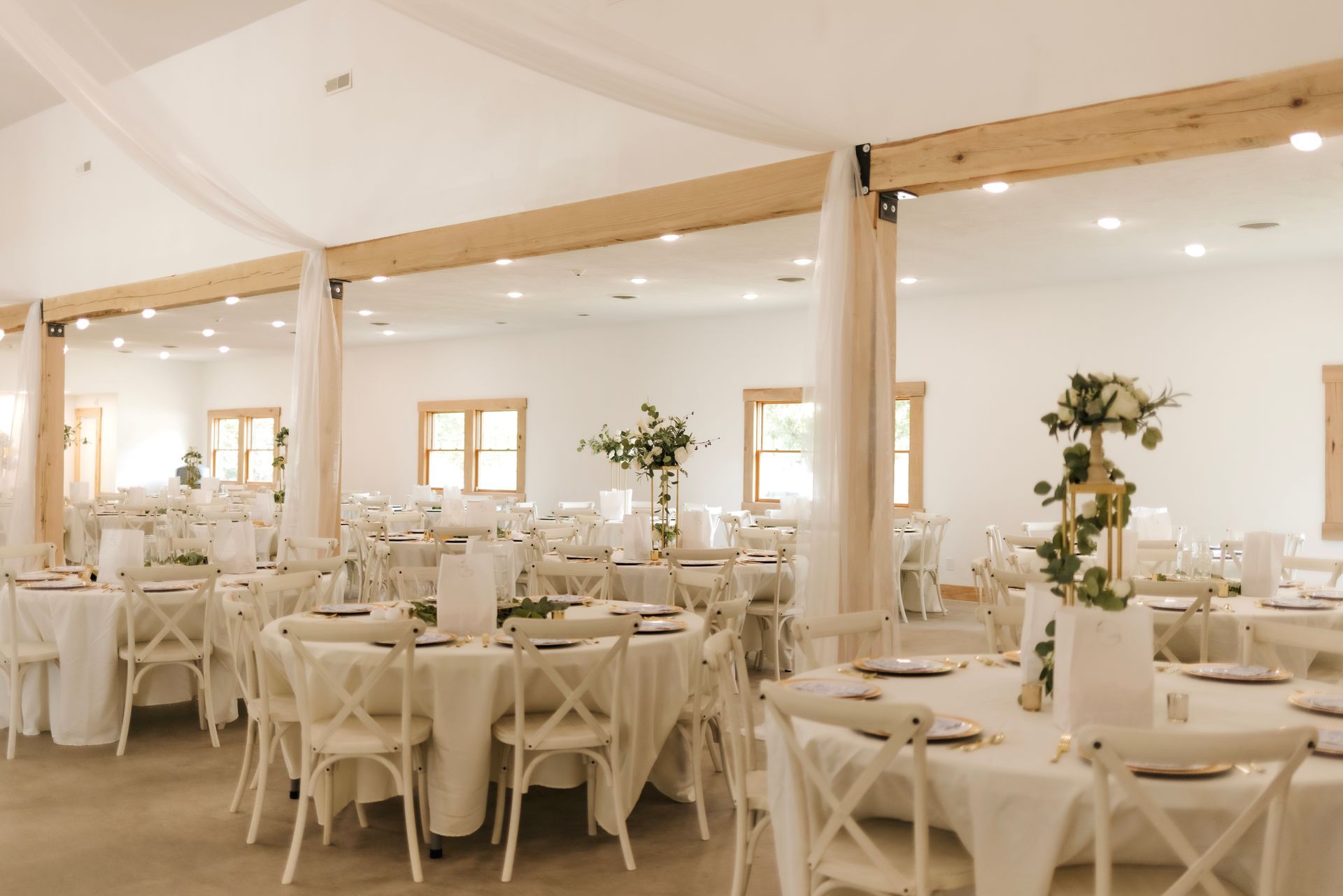 A large room with tables and chairs set up for a wedding reception.