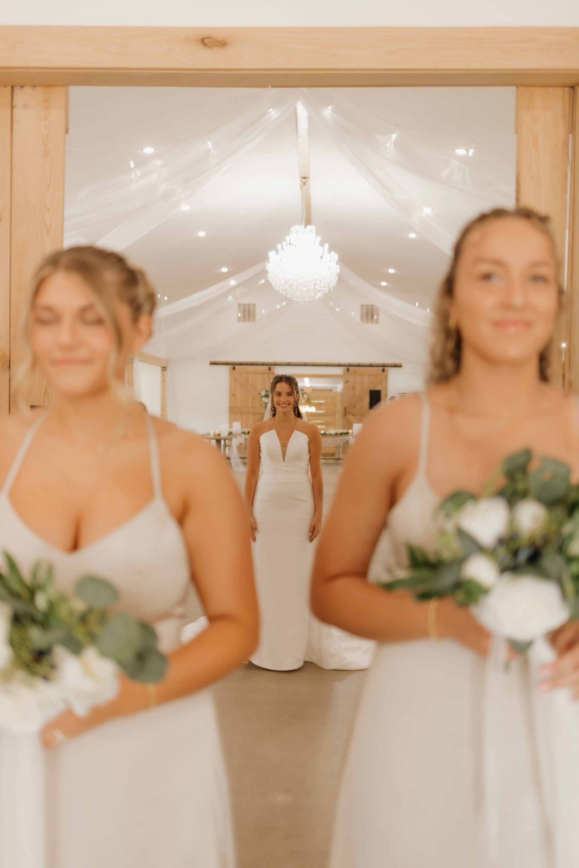 A bride and her bridesmaids are standing in a room holding flowers.