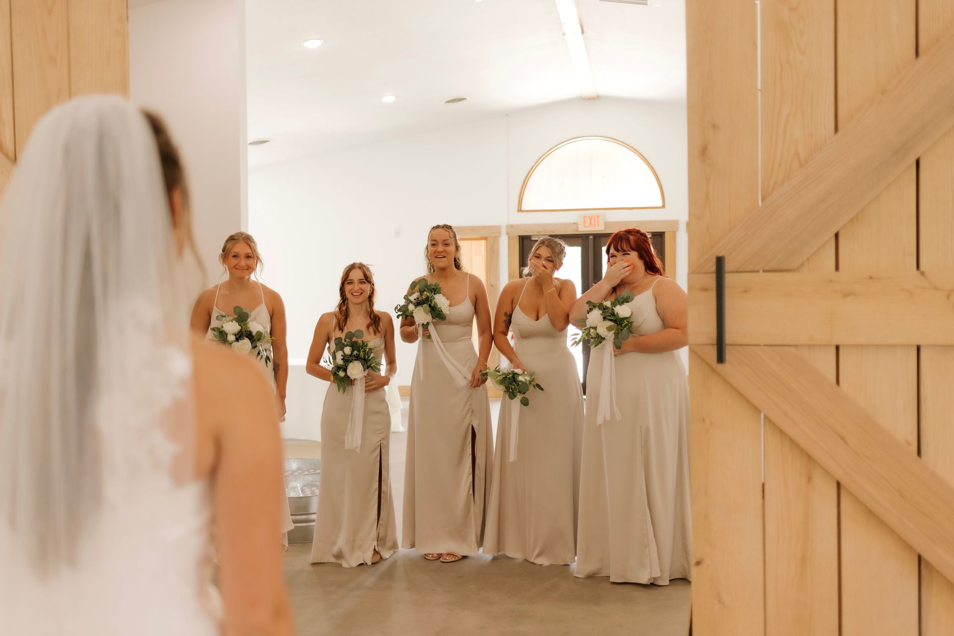 A bride and her bridesmaids are standing in front of a wooden door.