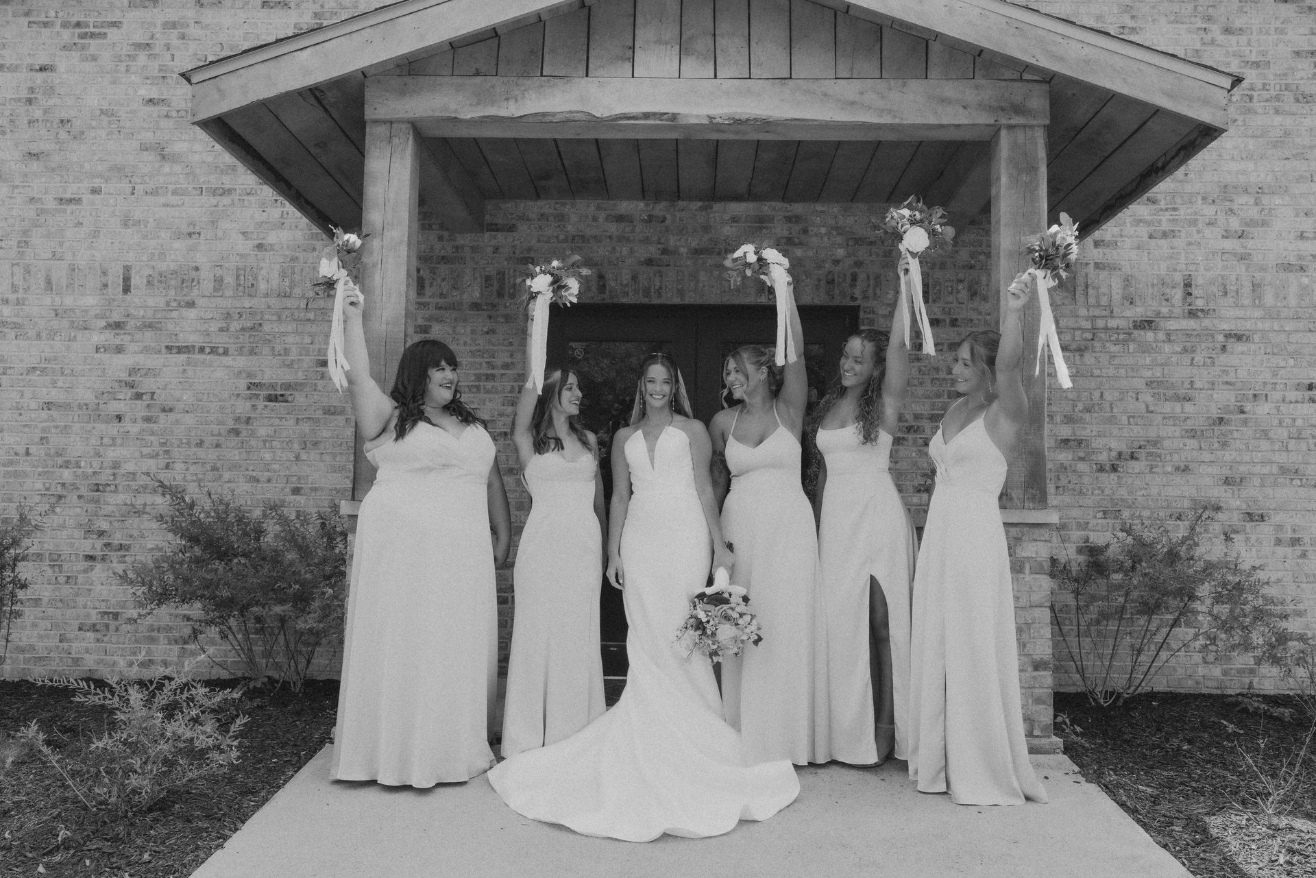 A bride and her bridesmaids are posing for a picture in front of a church.
