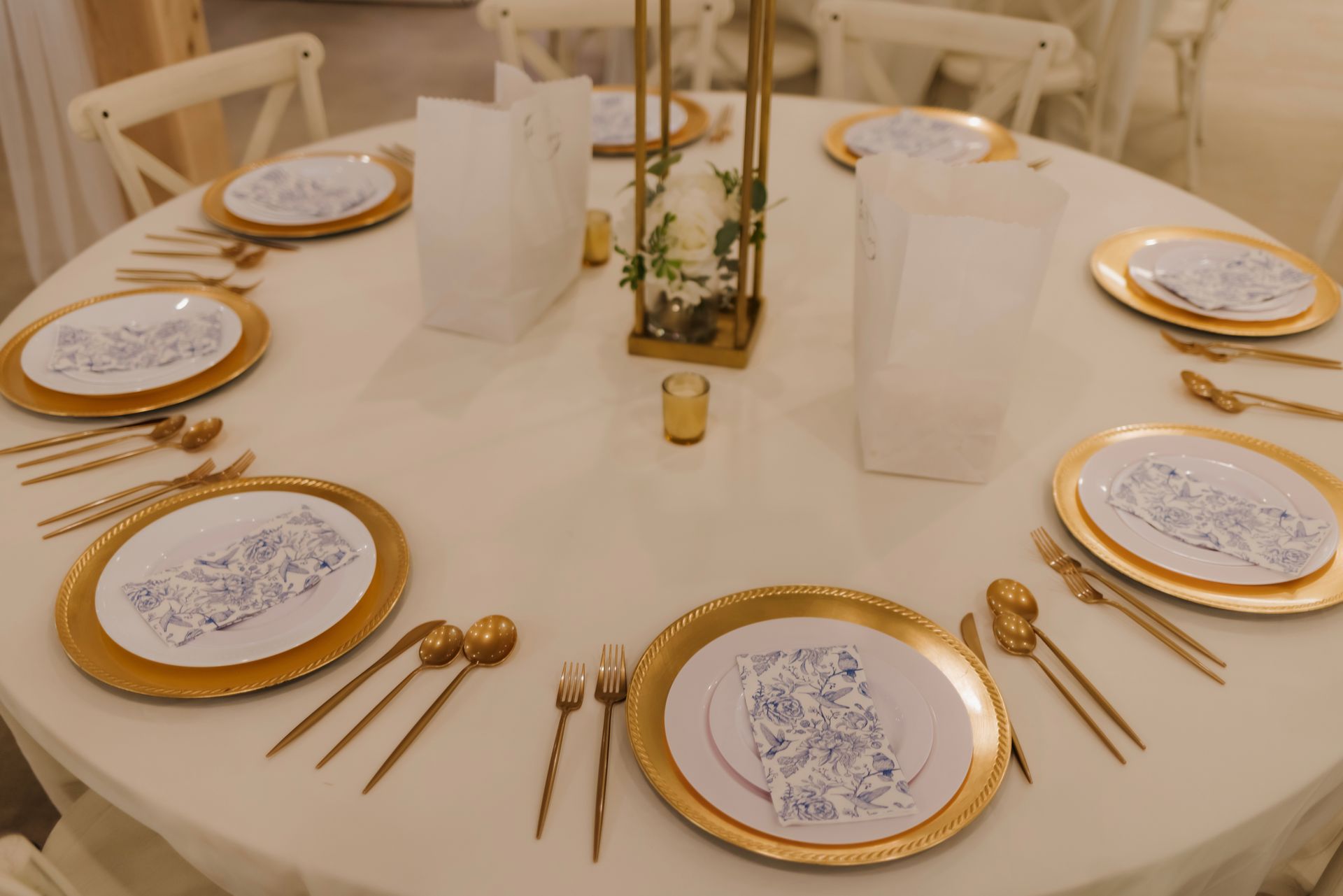 A round table with plates , silverware , and candles on it.
