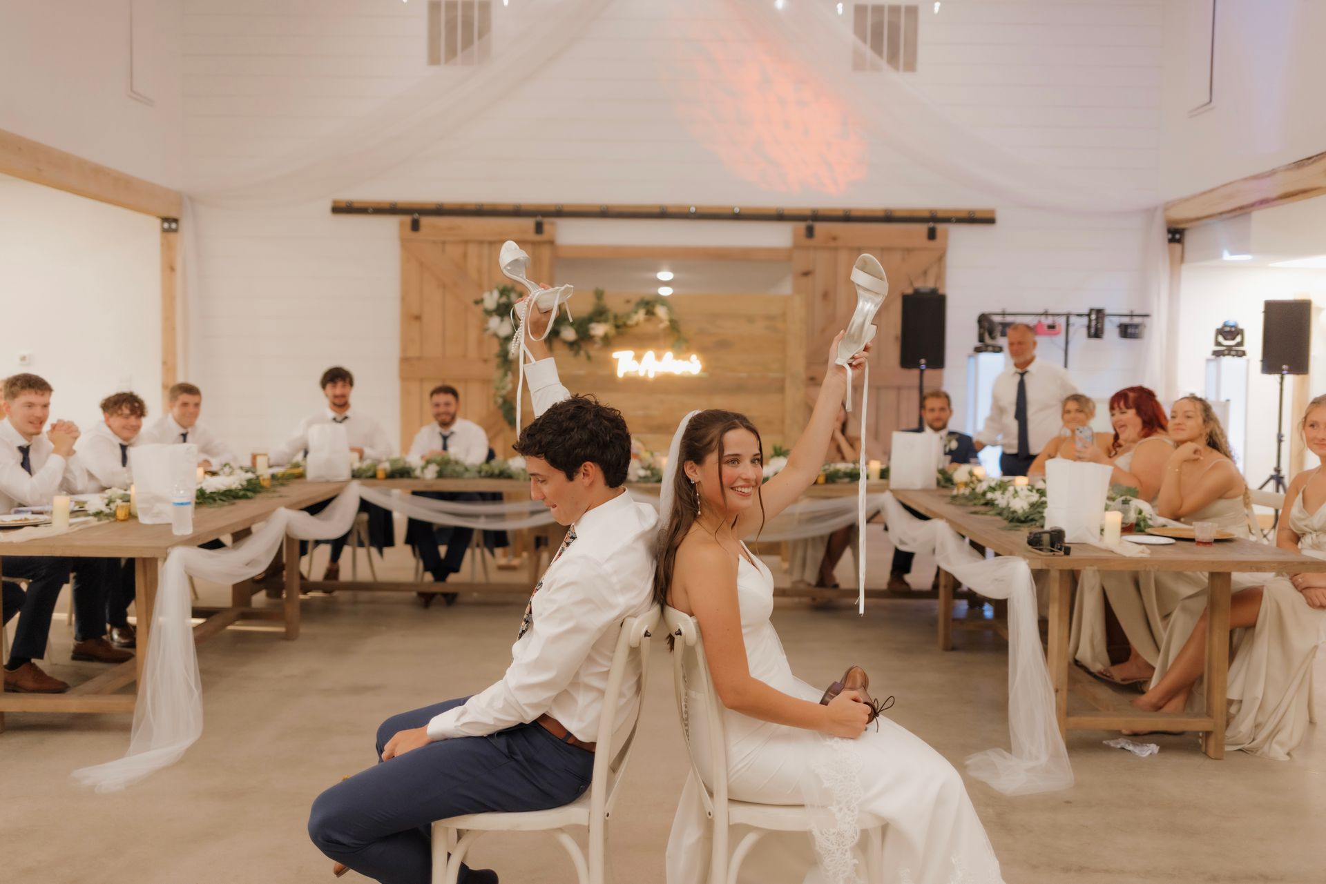 A bride and groom are sitting in chairs at a wedding reception.